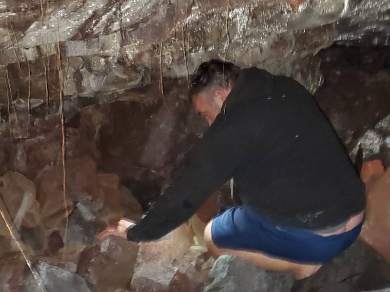 Jessie crouching among volcanic rock inside the tube